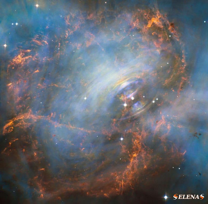Пульсар: красно-синие туманные детали с голубовато-белыми кольцами вокруг очень яркой звезды в центре.